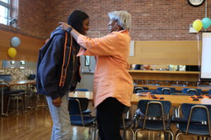 Faculty advisor Janet Pugh puts a sash around the neck of a student