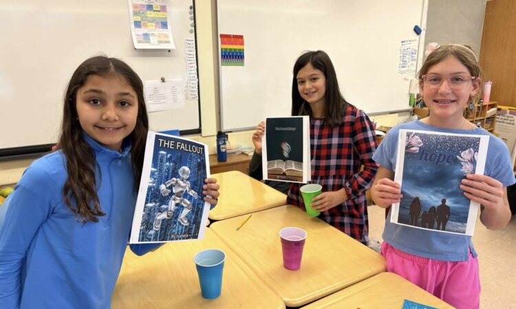 Three Ethical Culture Fieldston School Fieldston Lower students smile as they hold up their finished dystopian fiction stories.