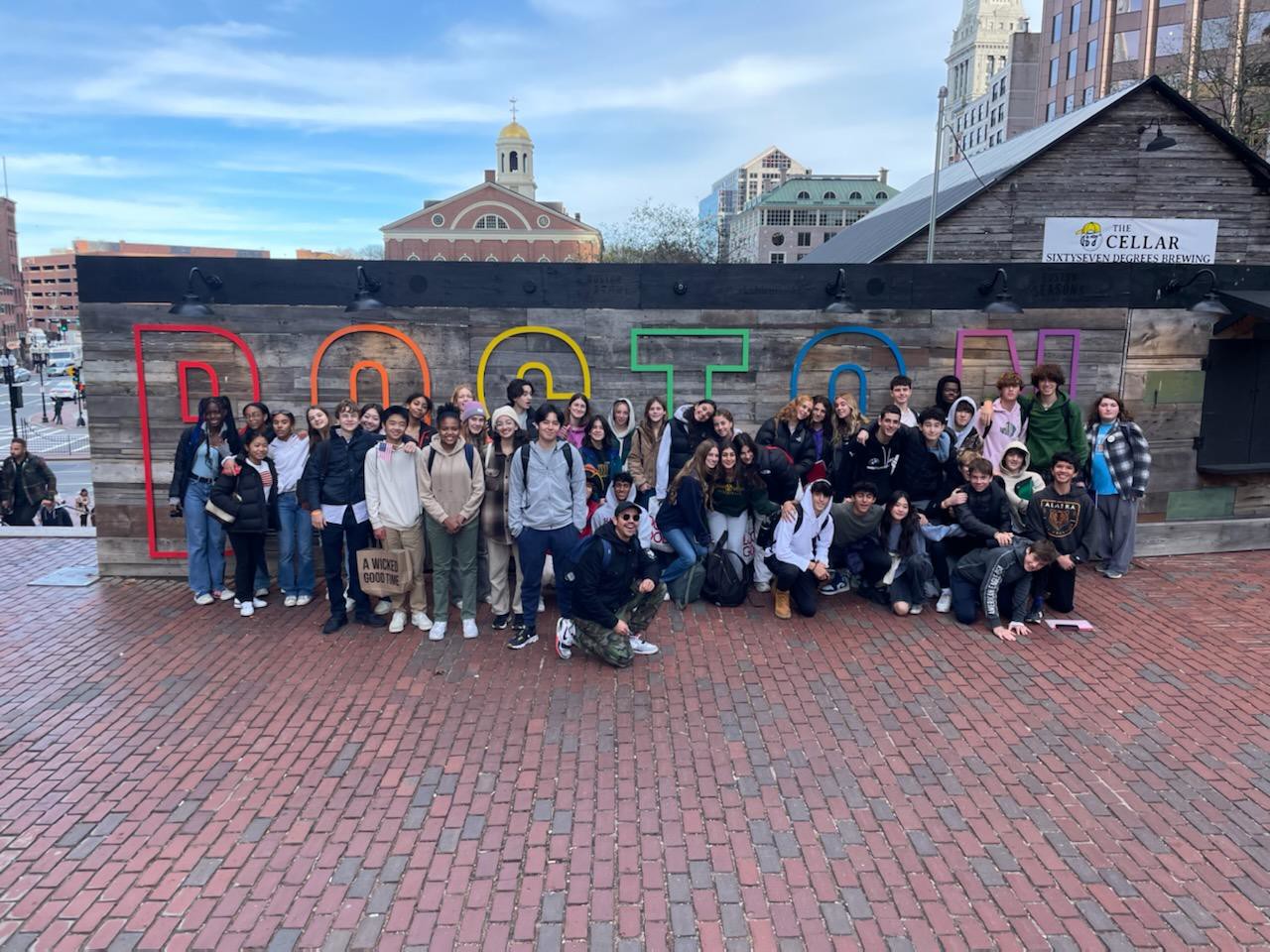 Fieldston Upper students pose in front of sign outdoors on their field trip to Boston.