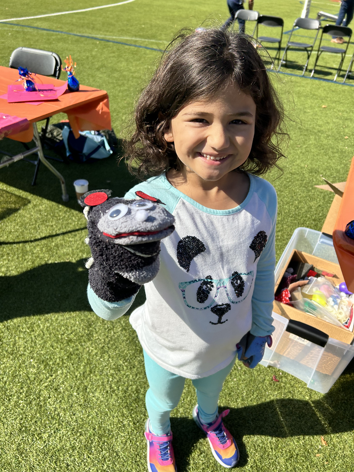 Fieldston Lower student poses with sock puppet on hand at Fall Carnival.