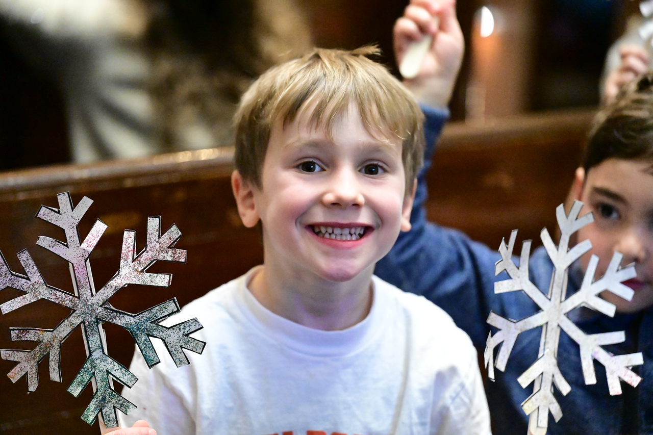 Ethical Culture student holds up snowflake at assembly.