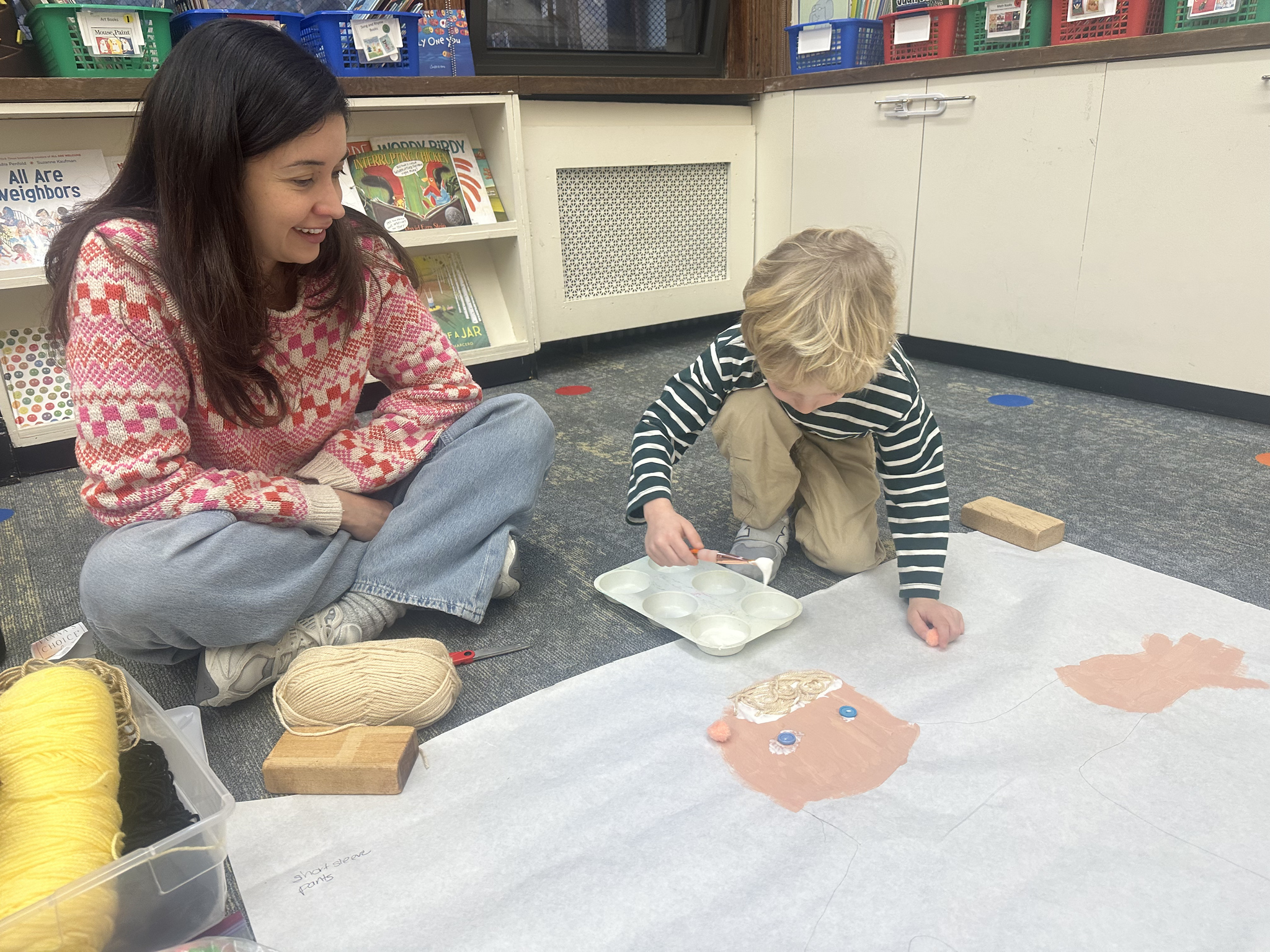 Ethical Culture Pre-K student works on "About Me" project with teacher's help in classroom.