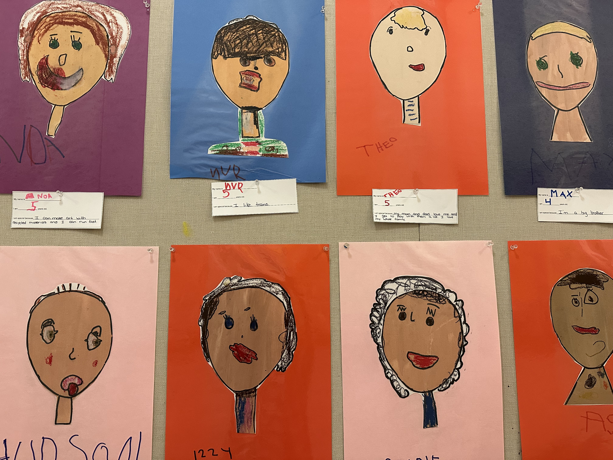 Bulletin board outside of Ethical Culture Pre-K classroom that shows students' self-portrait drawing art projects.