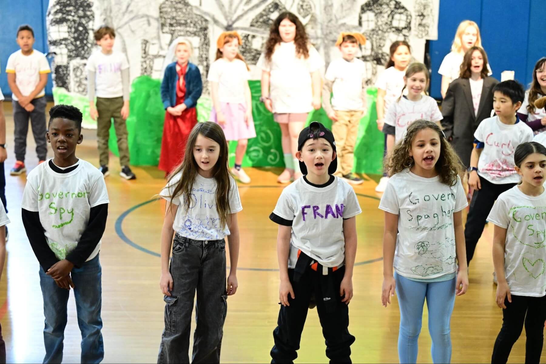 A group of Fieldston Lower 3rd Grade students stand center stage and sing during a performance of the 3rd Grade musical.