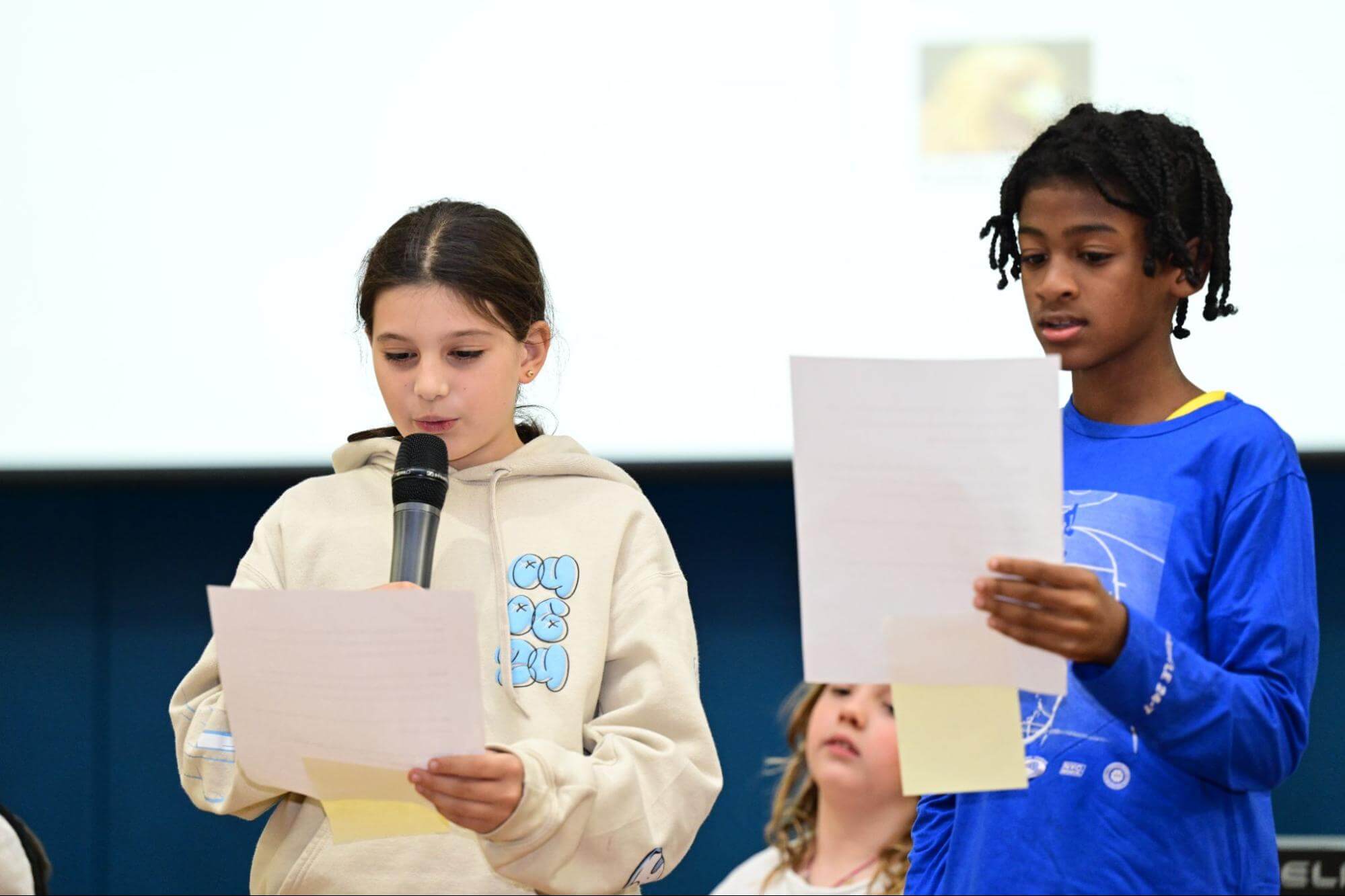 Two Ethical Culture Fieldston School Fieldston Lower students present at an assembly.