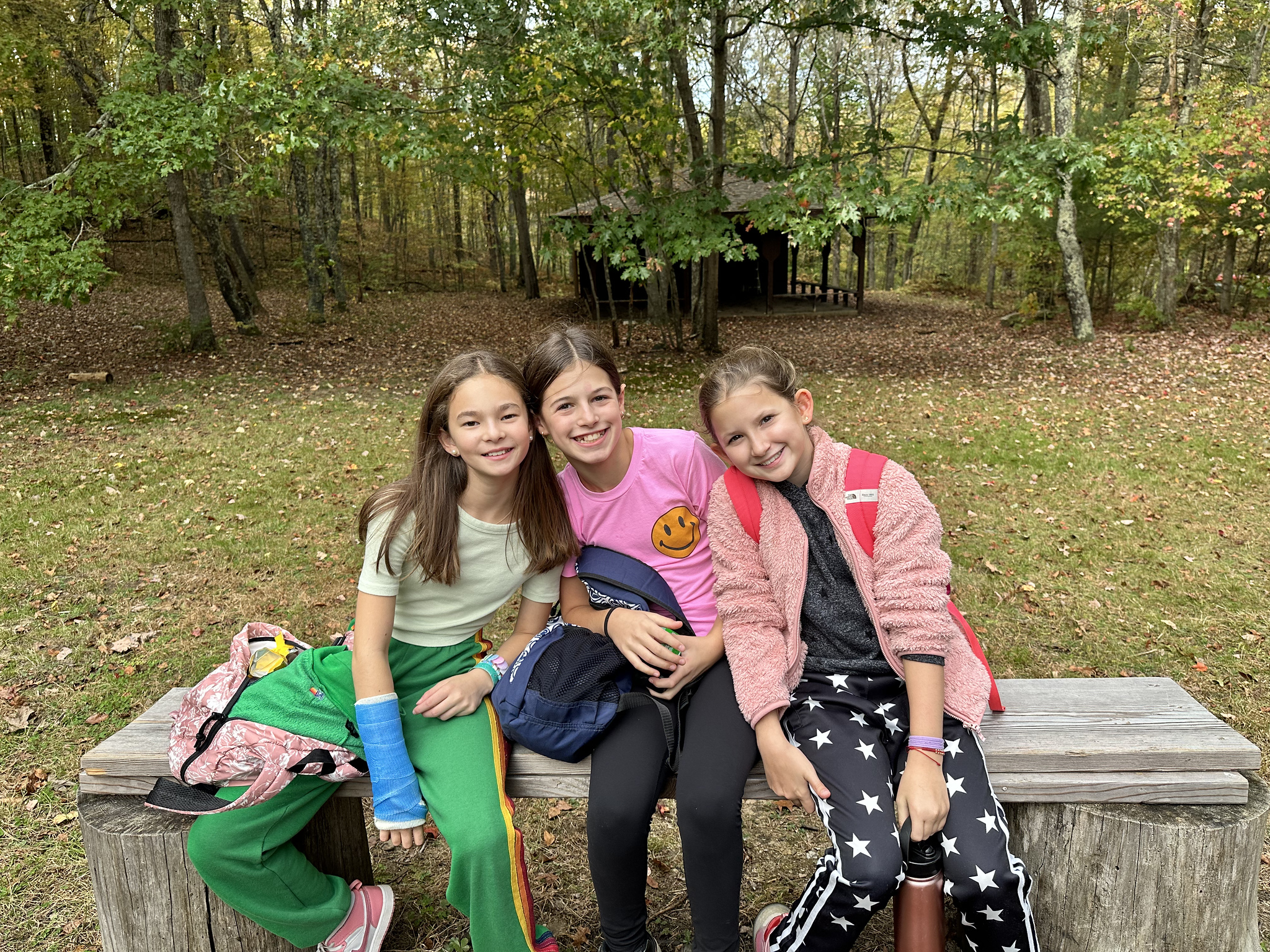 Ethical culture students pose and smile together around firepit at Nature's Classroom.