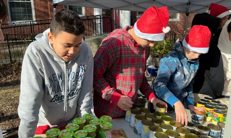 Three 7th Grade students at Ethical Culture Fieldston School sort donations of canned goods.