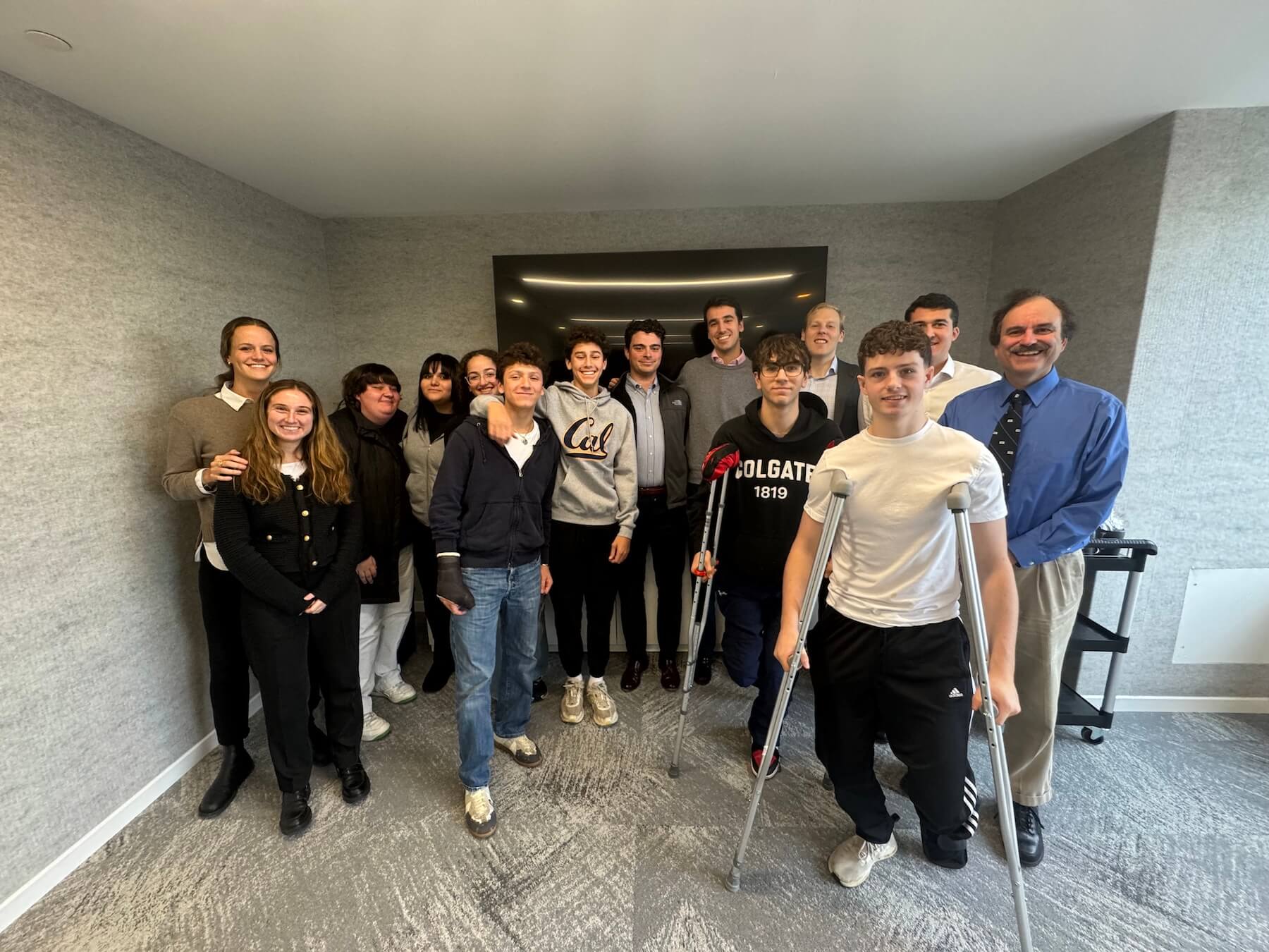 A Group of Ethical Culture Fieldston Upper School students pose for a photograph at an investment firm, smiling,