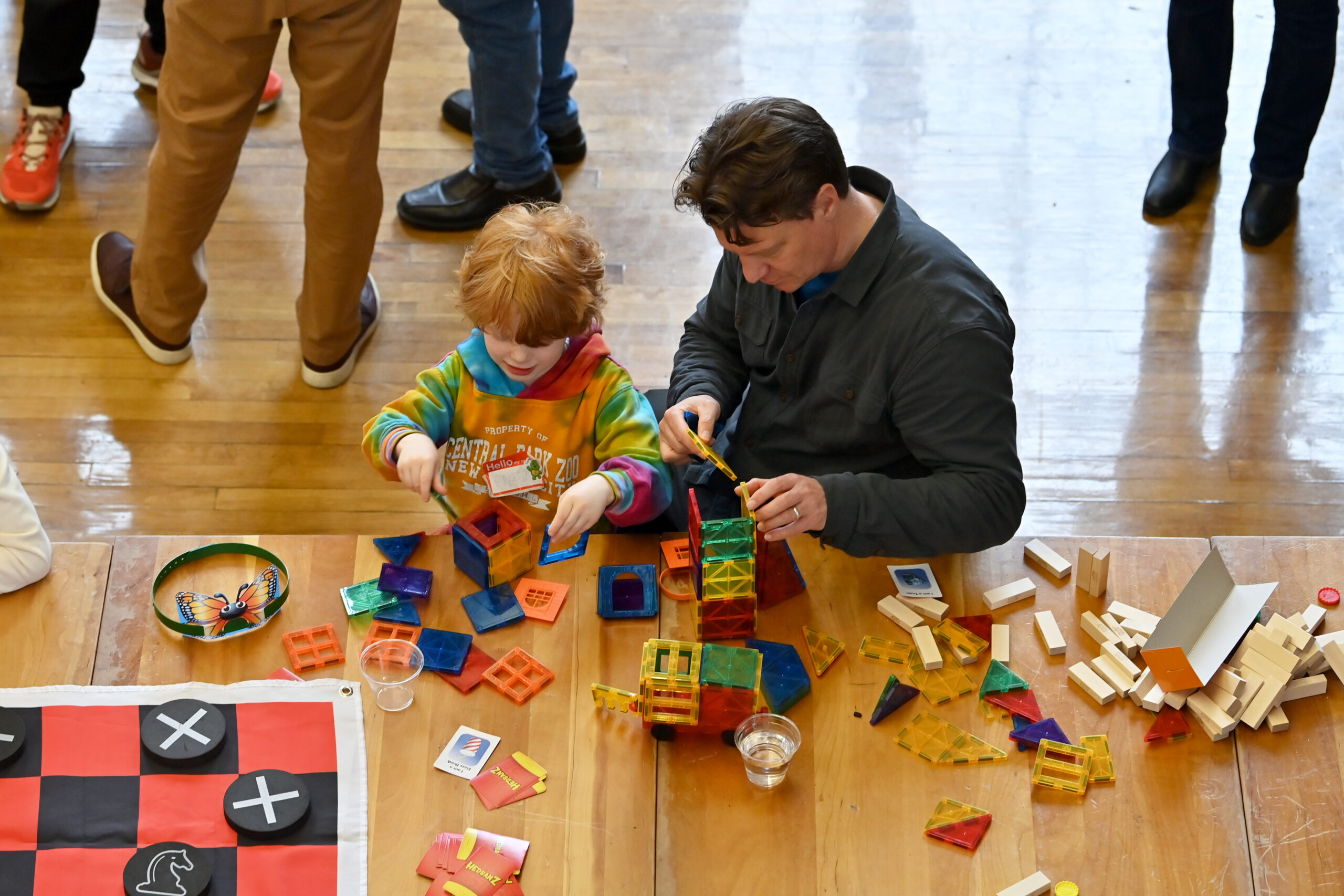 A photo from above showing an adult and a child plating with magnate blocks at a table