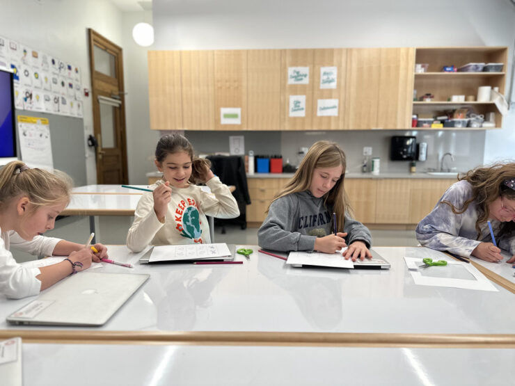 Ethical Culture students sit at desks and work on animation project together.